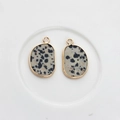 Close-up of natural Dalmatian Jasper pendants with gold plated edges on white ceramic - Leopard Print