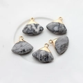 Macro detail of five fan-shaped agate pendants with gold metal edges on a tray - Black