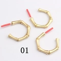 Detail of three gold alloy C-shape hoop earrings with textured bamboo design and red protective tubes - Bamboo Texture(01)