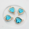 Close-up of four sky blue heart-shaped crystal charms with gold-plated copper frames - Lake Blue