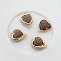 Close-up of four smoky faceted crystal heart charms with gold-plated copper frames - Brown