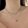 Nahaufnahme der doppellagigen Silberkette mit blauem Strass-Schmetterlingsanhänger am Model - Doppelschichtiger Schmetterling