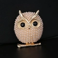 Golden owl brooch with white pearls and black gemstone eyes on black background - Golden Pearl Owl