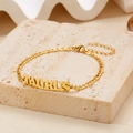 Golden stainless steel Taurus zodiac charm bracelet with lobster clasp on a stone surface - Gold Taurus