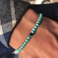 Men's 6mm turquoise stone beaded bracelet with blue evil eye charm on a male wrist - Turquoise