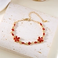 Details eines goldenen Blumenarmbands mit roten Kristallen auf weißem Stein - Armband Rot