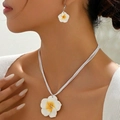 Elegantes weißes Plumeria-Schmuckset mit Kette und Ohrringen an einem Modell - Weiß