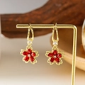 Elegante goldene Tropfenohrringe mit roten Kristallblüten auf einem Displayständer - Ohrringe Rot