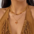 Dettaglio della collana dorata a strati con pendente a foglia d'acero e perline marroni - Stile a Doppio Strato con Pietrisco