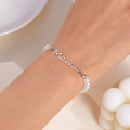 Vue rapprochée d'un bracelet en perles avec pendentif Mama porté au poignet, tons doux - Bracelet de perles / Argent