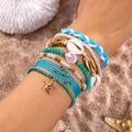 Detail of bohemian beach bracelet set with starfish charm and sea shells on sand - Style 3
