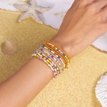 Close-up of bohemian multi-layer seed bead bracelets with shells on a beach setting - Style 8