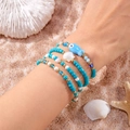 Detail of four-piece bohemian beaded bracelet set with fish and shell charms on beach - Style 13