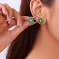 Deep green daisy stud earrings with golden centers shown on a model's earlobe - Short Stud Earrings Green