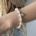 Detail of baroque pearl bracelet with gold starfish and seashell charms on model's wrist - Bracelet