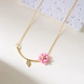Ketting met roze madeliefje hanger, gouden ketting en blad op een stenen ondergrond - Roze Ketting