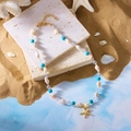 Detail einer Strandhalskette mit Muscheln, türkisen Perlen und goldenem Seestern-Anhänger - Blaue Seestern-Halskette