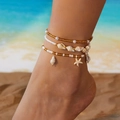 Detail von mehrlagigen Strand-Fußkettchen mit Seesternen, Muscheln und Perlen am Meer - 3er Set / Gold & Seestern-Seeschnecken-Anhänger