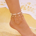Detail of layered beach anklet featuring starfish and shells on a sandy background - Set of 3 / Gold & Multiple Sea Snail Charms