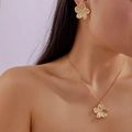 Détail d'une parure florale en or mat avec texture en métal brossé sur le collier et les boucles - Ensemble Collier Boucles d'Oreilles Fleur