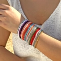 Dettaglio di un set di braccialetti elastici bohémien con perline colorate sul polso - Set da 20 Pezzi / Colorato