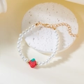 Detail einer Perlenkette mit Erdbeer-Anhänger auf einem weißen Displayständer - Armband / Rote Erdbeere