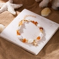 Boho-Muschelarmband mit Bernsteinkies und goldenem Seestern-Anhänger am Sandstrand - Armband-Braun