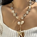 Detail of layered seashell necklace featuring a gold starfish and pearl pendant on model - Iridescent Mother-of-Pearl Starfish Pendant Style (NC25Y0356-1)
