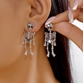 Nahaufnahme der silbernen Totenkopf-Ohrringe mit Skelett-Anhänger am Ohr - Strass Totenkopf Stecker Skelett Stil (ER25Y0145) / Silber