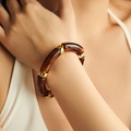 Detail of amber resin tube bracelet with polished gold metal rings on a model wrist - Deep Amber Tortoise (AB0008-4)