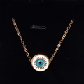Macro detail of golden Evil Eye pendant with blue enamel inlay on a black display - White