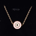 Macro shot of gold-plated evil eye necklace with pink enamel and radial eyelashes detail - Pink
