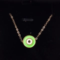 Detailed close-up of a gold Evil Eye pendant with vibrant neon green enamel on black velvet - Grass Green
