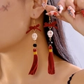 Close-up of gothic earrings with red velvet bow, skull bead and long suede tassels - Burgundy