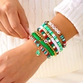Nahaufnahme von Weihnachts-Armbändern mit Tannenbaum-Anhänger auf einem Strickpullover - Herz Weihnachtsbaum