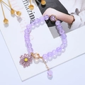 Detailed shot of purple beaded bracelet with daisy charm on an open fashion magazine - Purple Daisy (BR22Y0142-5)