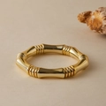 Detailed view of a golden bamboo-jointed bracelet on a textured beige background - Bright Gold Metallic (AB0070-5)