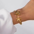 Eleganter goldener Edelstahl-Armreif mit poliertem Blumendesign am weiblichen Handgelenk - Lilienblüten Offener Stil (BR25Y0722-9)
