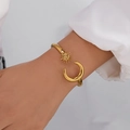 Goldener offener Armreif mit Sonnen- und Mondmotiven am Handgelenk einer Frau - Vintage Sonne und Mond Himmlischer Stil (BR25Y0721)