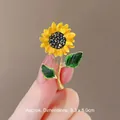 Elegant sunflower brooch featuring yellow petals and black rhinestones held in hand - Bright Yellow Petal Green Enamel Leaf Sunflower Style (BC23Y0115-3)