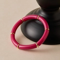 Detailweergave van de roze bohemien buisarmband met gouden tussenringen op een display - Rozerood (AB0091-20)