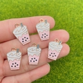 Detail of five pink pearl milk tea charms held by hand over green grass background - Pink