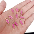 Macro view of a gold lightning bolt charm with pink enamel inlay on palm for size scale - Rose Red