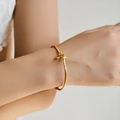 Gros plan d'un bracelet à nœud minimaliste plaqué or 18 carats sur le poignet d'une femme - Style Design de Nœud (KB0474)
