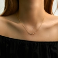 Golden necklace with a leaf-shaped pendant featuring white cubic zirconia on a model - Fresh Branch Leaf Style (KN0265)