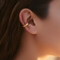Close-up of gold ear cuff featuring an intricate wheat grain texture on model ear - Braided Wheat Texture Style (KE1473)