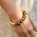 Detail of leopard print and gold metal segments on an elastic bracelet worn by a model - Heart Leopard Style (AB0009-23) / Yellow and Black