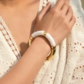 Detail of beaded bracelet with white and gold curved tubes worn on a female wrist - Glossy Patchwork Style (AB0009-25) / Pure White