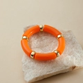 Detail of bamboo-style orange acrylic bracelet on white stone with gold spacers - Bright Orange (AB0008-21)