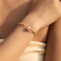 Bracelet élégant à maillons trombone dorés avec une perle rose sur le poignet d'une femme - Style Chaîne Trombone Épissée Perle Rose Violet (KB0697)